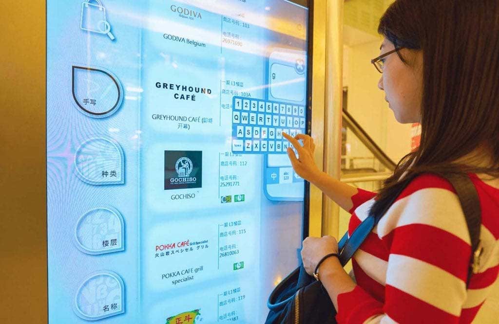 Interactive-digital-signage-Navori-QL-Lady-interacts-with-touchscreen-at-a-shopping-center-in-hong-kong